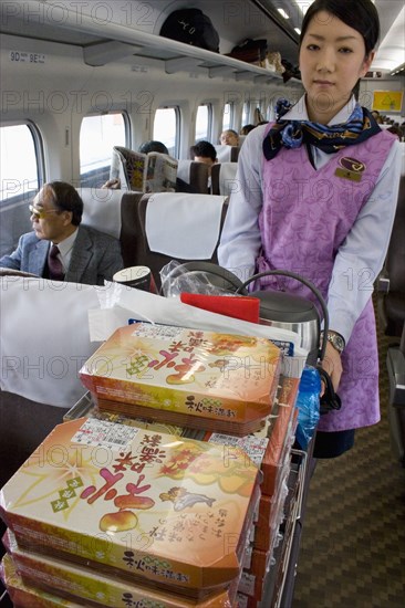 JAPAN, Honshu, "Shinkansen train series 700, the ‘bullet train’ travelling between Tokyo and Kyoto.  Train hostess serving bento lunchboxes and refreshments from trolley. "