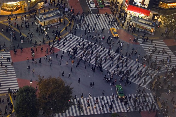 JAPAN, Honshu, Tokyo, "Shibuya District.  Meiji-dori with Dogen-Zaka junction outside Shinjuku Station.  View from above over one of the busiest junctions in the world with crowds on pedestrian crossings, waiting traffic and lights from surrounding buildings at dusk."