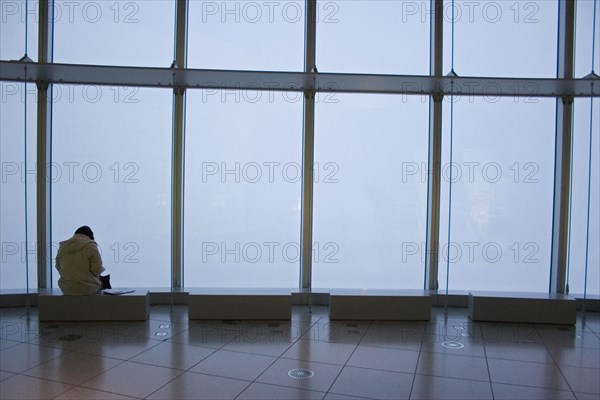 JAPAN, Honshu, Tokyo, Woman sitting alone at one of the benches in the Tokyo Art Museum and exhibition hall.
