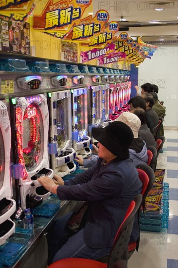 JAPAN, Honshu, Tokyo, "Shinjuku, Kabuki-cho.  Japanese men and women betting on electronic gambling machines."