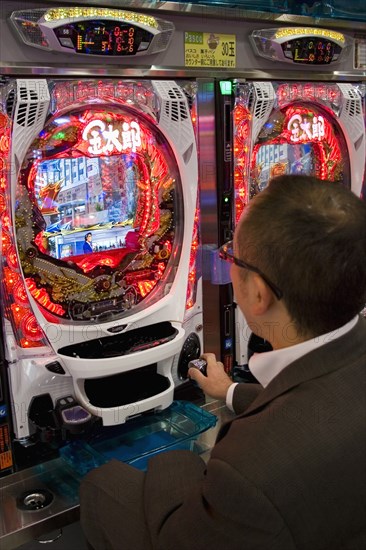 JAPAN, Honshu, Tokyo, Shinjuku. Japanese man gambling at electronic machine
