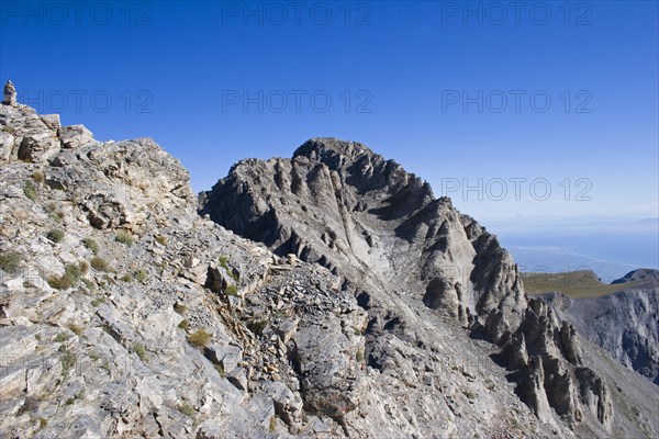 GREECE, Macedonia, Pieria, "View of  highest peak of Mount Olympus called Mytikas.  Eroded rocks and scree against blue, cloudless sky."