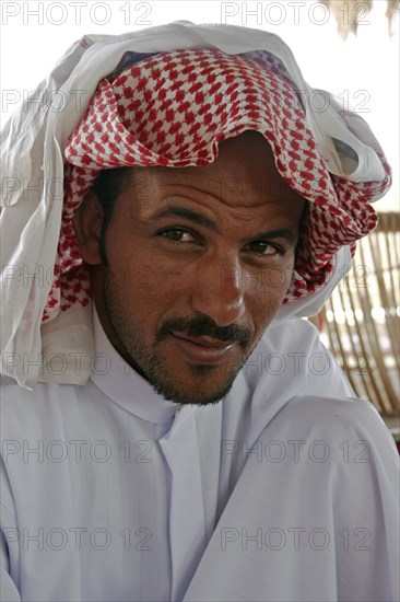 EGYPT, Sinai Desert, Ras el Satan, "Portrait of a Bedouin man with short, trimmed beard and moustache, wearing traditional Arabic dress of keffiyeh and jalabiya."