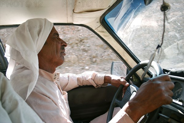 EGYPT, Sinai Desert, Ras el Satan, "Bedouin taxi driver wearing traditional Arabic dress of keffiyeh and jalabiya, singing while driving."