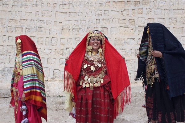TUNISIA, Sahara, Tozeur, "Three Tunisian women wearing traditional dress, golden jewelry and ornaments, relatives of a Tunisian bride whose wedding they are celebrating on the borders of the Sahara Desert."