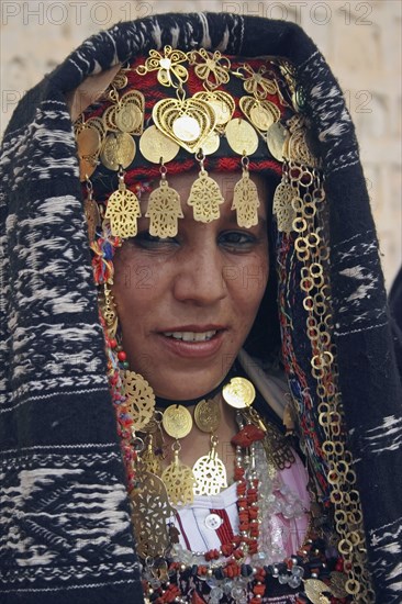 TUNISIA, Sahara, Tozeur, "Head and shoulders portrait of Tunisian bride wearing traditional dress, gold jewelry and decorated head dress in preparation for her wedding held on the edge of the Sahara Desert."
