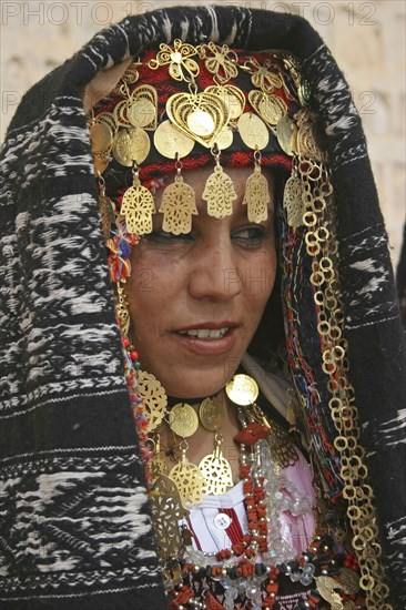 TUNISIA, Sahara, Tozeur, "Head and shoulders portrait of Tunisian bride wearing traditional dress, gold jewelry and decorated head dress in preparation for her wedding held on the edge of the Sahara Desert."