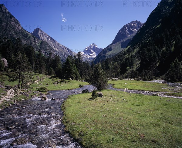FRANCE, Midi-Pyrenees, Hautes-Pyrenees, Vallee de Lutour.  View south over lower valley with central snow covered peak of Pic de Labas 2927 m / 9586 ft south of Cauterets.  Sparkling river and trees.