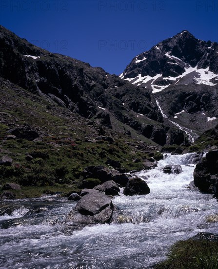 FRANCE, Midi-Pyrenees, Hautes-Pyrenees, Vallee du Lutour.  Upper valley view south towards snow covered peak of Pic de Labas 2927 m / 9586 ft with stream Gave d’Estrom Soubiran in foreground.