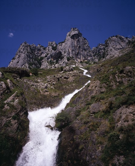 SPAIN, Asturias, Picos de Europa, "Artificial waterfall, overflow from Canal de Poncebos which supplies the hydro-electric plant at Poncebos with jagged limestone cliffs of Cueto del Pando above. "