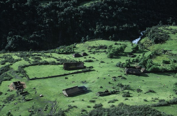PERU, Ayacucho Province, Lijiana, Aerial view over settlement amongst green agricultural landscape next to a fast flowing river with horses and livestock seen on the ground