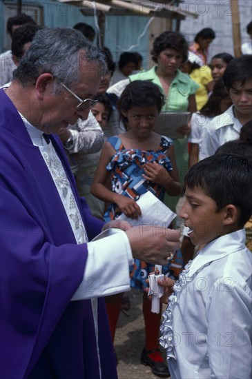ECUADOR, Guayas Province, Guayaquil , Roman Catholic Bishop giving Communion in Barrio Indio Guayas slum neighbourhood.