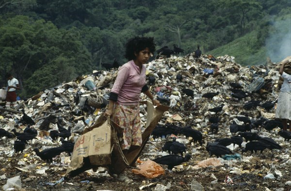 ECUADOR, Guayas Province, Guayaquil , The city rubbish tip with a girl searching for items to recycle amongst waste with black vulture birds scavenging.