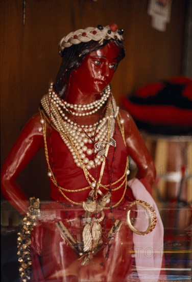 BRAZIL, Salvador da Bahia, Red statue of Jesus Christ used in Umbanda ceremonies adorned with pearl necklaces and gold jewellery . A Yoruba Christian cult