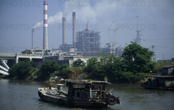 CHINA, Jiangsu Province, Transport, Boat travelling down the Grand Canal between Suzhou and Wuxi. Power station with smoke emitting from cooling towers and large industrial buildings under construction.