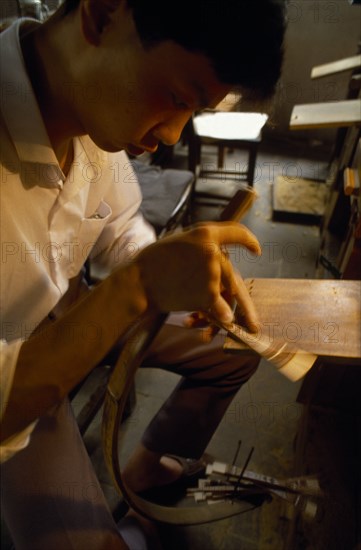 CHINA, Jiangsu Province, Suzhou, Man hand cutting with saw sandalwood fans