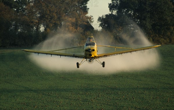 ENGLAND, West Sussex, Slinfold, Yellow plane crop spraying