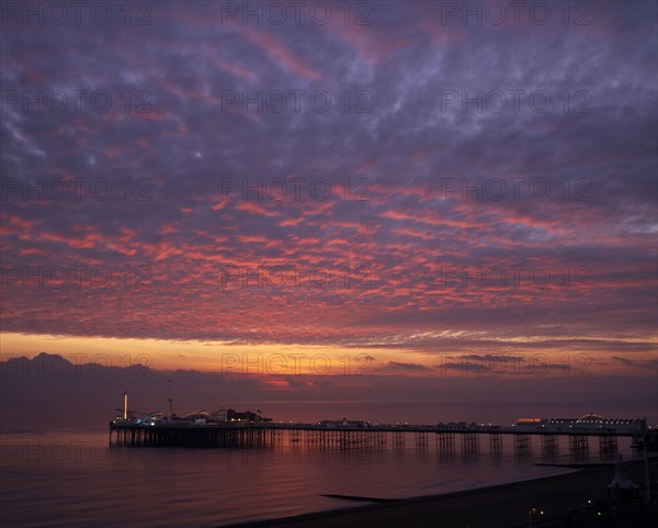 ENGLAND, East Sussex, Brighton, Early Autumn sunset from Marine Parade with Brighton Pier and street lights illuminated.