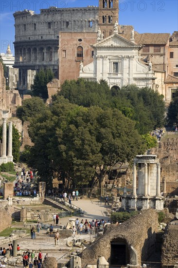 ITALY, Lazio, Rome, View of The Forum with the Colosseum rising behind the bell tower of the church of Santa Francesca Romana with tourists and the Temple of The Vestals in the foreground