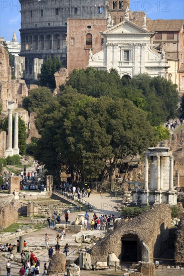 ITALY, Lazio, Rome, View of The Forum with the Colosseum rising behind the bell tower of the church of Santa Francesca Romana with tourists and the Temple of The Vestals in the foreground