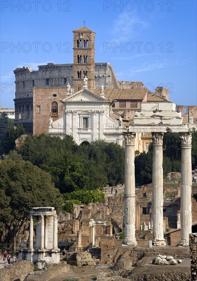 ITALY, Lazio, Rome, View of The Forum with the Colosseum rising behind the bell tower of the church of Santa Francesca Romana with the Temple of The Vestals and the three Corinthian columns of the Temple of Castor and Pollux in the foreground