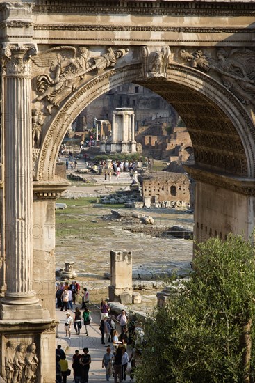 ITALY, Lazio, Rome, Tourists walking in the Forum with the Temple of The Vestals seen through the Arch of Septimius Severus