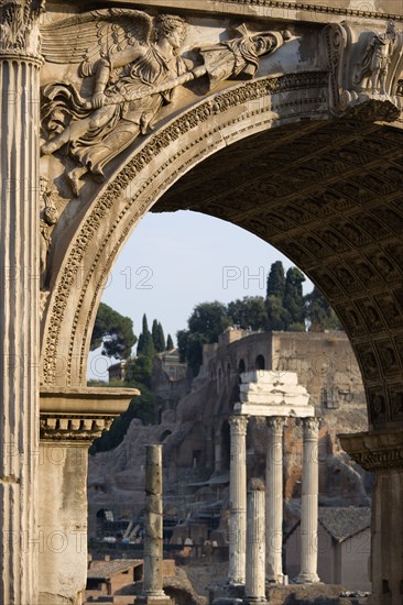 ITALY, Lazio, Rome, The three Corinthian columns of the Temple of Castor and Pollux and the walls of the Palatine seen through the Arch of Septimius Severus in the Forum