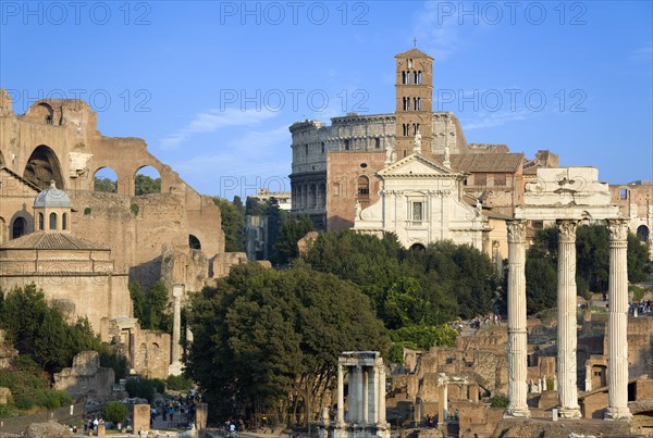 ITALY, Lazio, Rome, View of The Forum with the Colosseum rising behind the bell tower of the church of Santa Francesca Romana with tourists and the Temple of The Vestals and the three Corinthian columns of the Temple of Castor and Pollux on the right and the Temple of Romulus and the Basilica of Constantine and Maxentius on the left