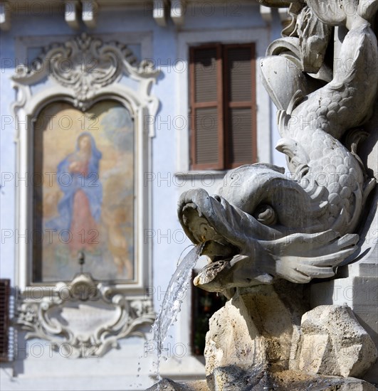 ITALY, Lazio, Rome, Detail of a dolphin on the Fountain of Piazza Della Rotonda by Giacomo Della Porta in 1575 with a religious fresco on the wall of a building beyond