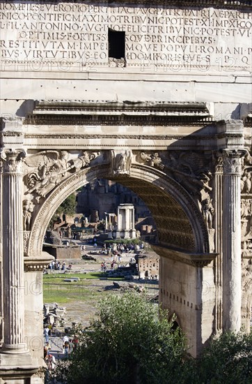 ITALY, Lazio, Rome, The floor of the Forum with tourists and the remains of the Temple of Vesta seen through the triumphal Arch of Septimius Severus