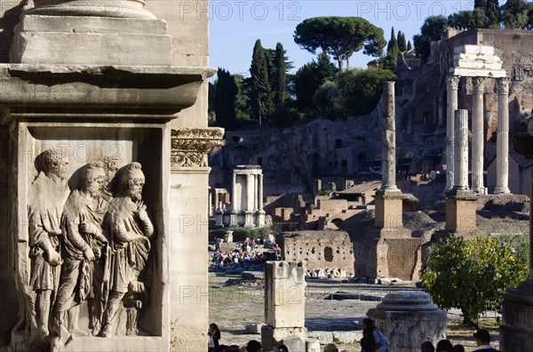 ITALY, Lazio, Rome, The floor of the Forum with tourists. A detail of the Arch of Septimius Severus the Temple of Vesta and the three Corinthian columns of the Temple of Castor and Pollux in front of the Palatine hill