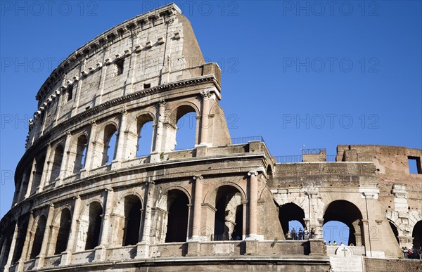 ITALY, Lazio, Rome, Detail of The Colosseum amphitheatre exterior with tourists walking past built by Emperor Vespasian in AD 80 in the grounds of Domus Aurea the home of Emperor Nero