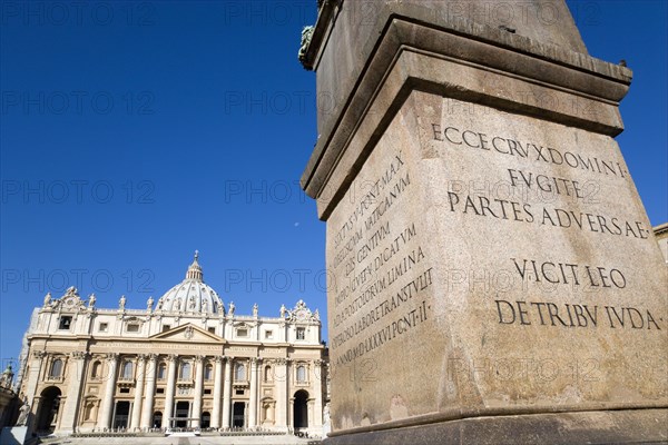 ITALY, Lazio, Rome, Vatican City The Basilica of St Peter with tourists at the entrance and a detail of the base of the Obelisk in the foreground