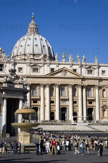 ITALY, Lazio, Rome, Vatican City The Basilica of St Peter with tourists at the entrance and in the Piazza San Pietro beside a water fountain