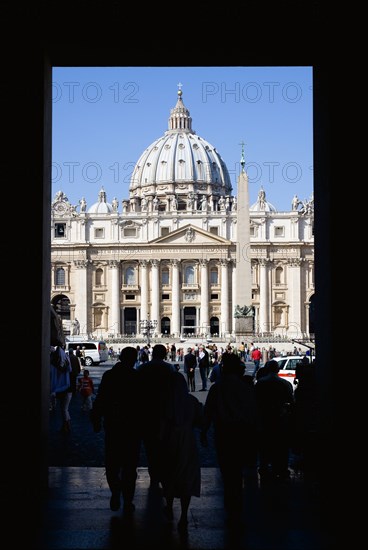 ITALY, Lazio, Rome, Vatican City Silhouette of tourists passing through an arch leading to the Piazza San Pietro or St Peter's Sqaure with the Basilica of St Peter beyond