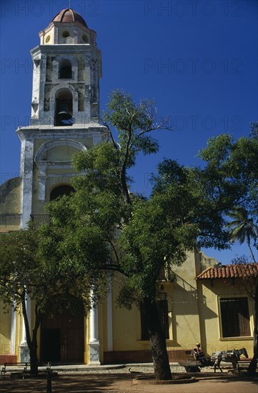 CUBA, Trinidad de Cuba, "Exterior of the former church now a museum of the revolutionary struggle. National Museum of the Struggle Against the Bandits, previously a church and convent of San Francisco. Passing horse drawn cart, tree in foreground."