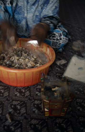 OMAN, Salalah, Trader bagging up frankincense for sale in souk.