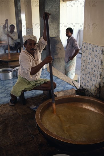 OMAN, Muscat, "Men stirring large, shallow dish of halva."