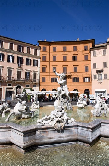 ITALY, Lazio, Rome, The Fountain of Neptune or Fontana del Nettuno in the Piazza Navona with tourists walking past restaurants beyond