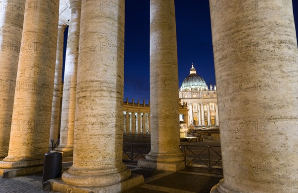 ITALY, Lazio, Rome, Vatican City The Basilica of St Peter seen through the pillars of the Ccolonnade by Bernini illuminated at night