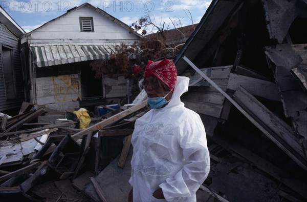 USA, Louisiana, New Orleans, "Aftermath of 2005 Hurricane Katrina, woman wearing protective clothing standing amongst wood and other debris from destroyed buildings."