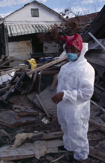 USA, Louisiana, New Orleans, "Aftermath of 2005 Hurricane Katrina, woman wearing protective clothing standing amongst wood and other debris from destroyed buildings."