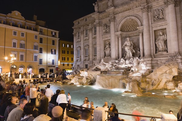 ITALY, Lazio, Rome, The 1762 Trevi Fountain by Nicola Salvi illuminated at night with tourists in the Piazza Di Trevi