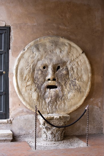 ITALY, Lazio, Rome, The Bocca della Verita or Mouth of Truth thought to be a medieval drain cover in the portico of the church of Santa Maria in Cosmedin. Tradition had it that the mouth would close over the hands of those who told lies