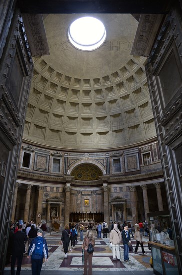 ITALY, Lazio, Rome, The interior of the Pantheon showing the oculus central opening and the coffering construction of the dome with tourists walking on the patterned marble flooring