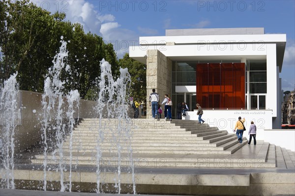 ITALY, Lazio, Rome, The fountain and steps with sightseers leading to the building hosuing the Ara Pacis or Altar of Peace built by Emperor Augustus to celebrate peace in the Mediteranean. The red prespex cube is part of a Valentino fashion exhibition at the museum
