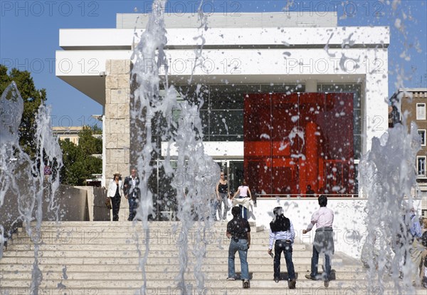 ITALY, Lazio, Rome, The fountain and steps with sightseers leading to the building hosuing the Ara Pacis or Altar of Peace built by Emperor Augustus to celebrate peace in the Mediteranean. The red prespex cube is part of a Valentino fashion exhibition at the museum