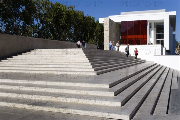 ITALY, Lazio, Rome, The steps with sightseers leading to the building hosuing the Ara Pacis or Altar of Peace built by Emperor Augustus to celebrate peace in the Mediteranean. The red prespex cube is part of a Valentino fashion exhibition at the museum