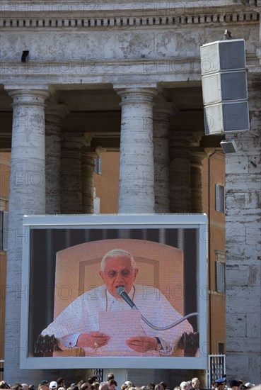 ITALY, Lazio, Rome, Vatican City Pilgrims in St Peter's Square for the wednesday Papal Audience in front of the Basilica watching Pope Benedict XVI Joseph Alois Radzinger with a cardinal on a large video TV monitor display