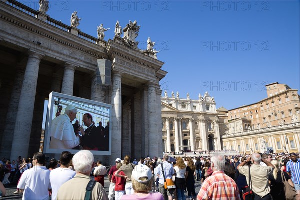 ITALY, Lazio, Rome, Vatican City Pilgrims in St Peter's Square for the wednesday Papal Audience in front of the Basilica watching Pope Benedict XVI Joseph Alois Radzinger with a cardinal on a large video TV monitor display